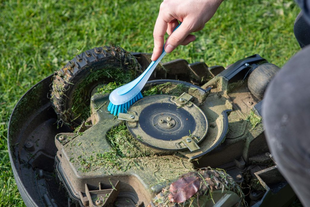 Person cleaning a robotic lawn mower.