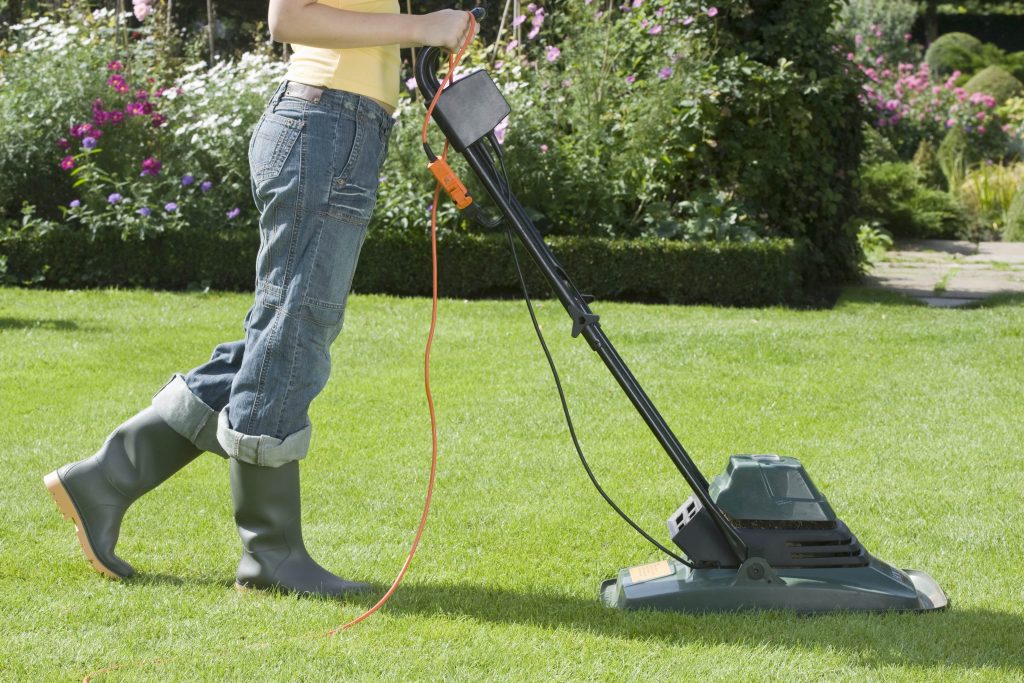 Woman using a small corded hover mower.