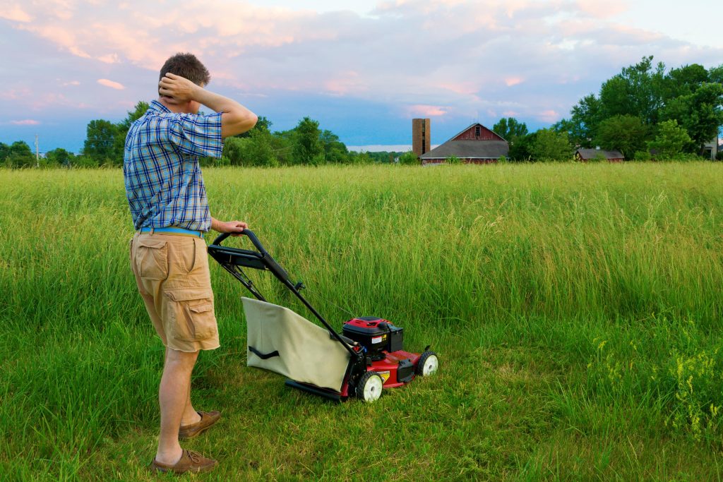 Man trying to cut extremely long grass.