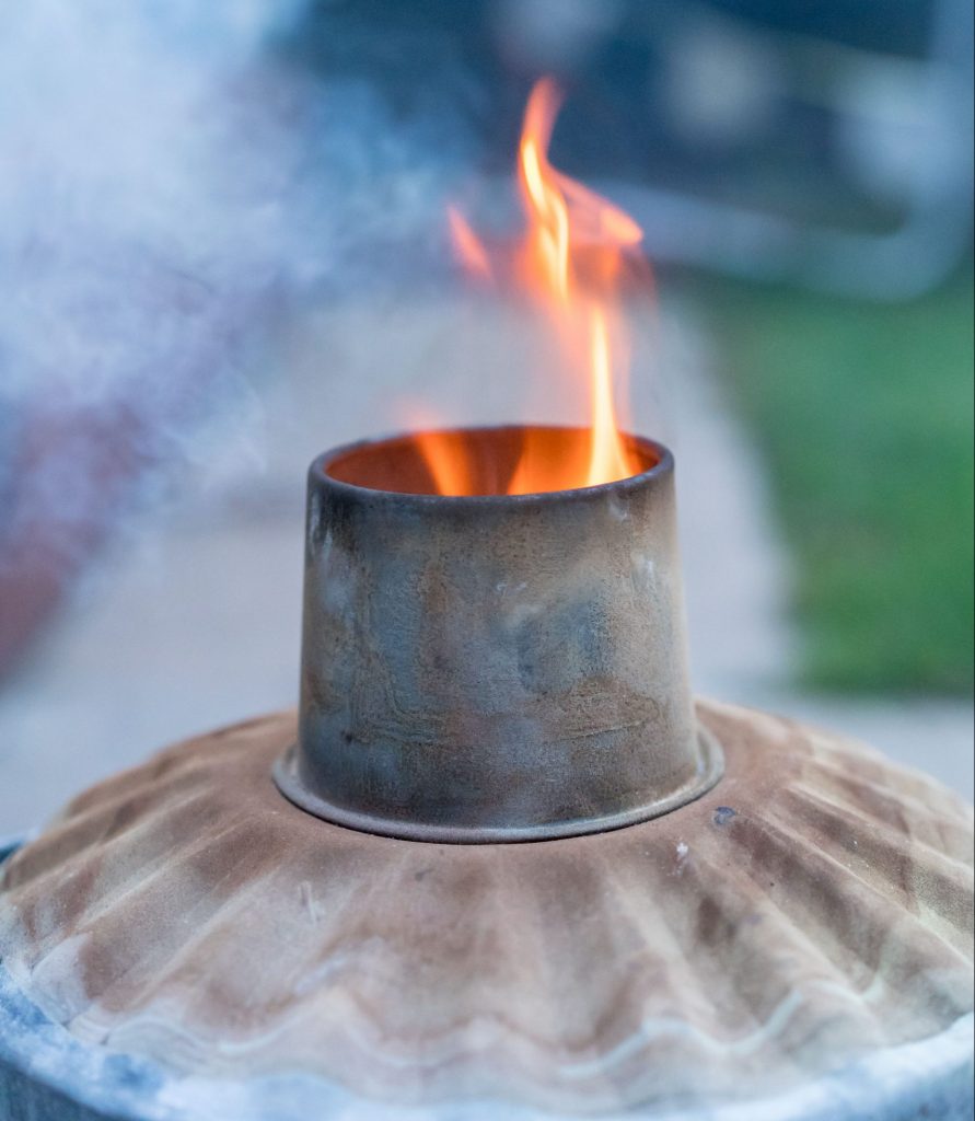 Garden incinerator with fire coming out of its chimney.