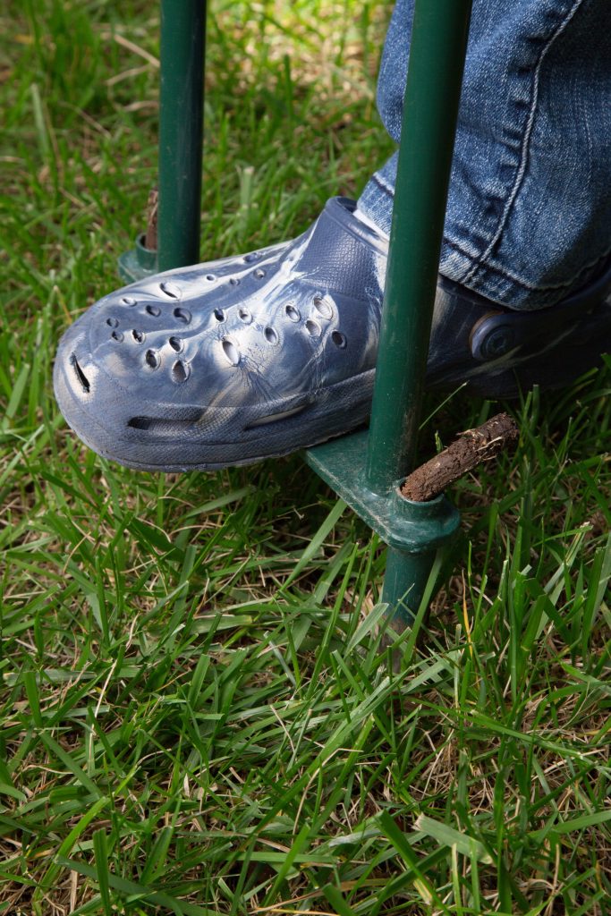 Person using hollow tine aerator.