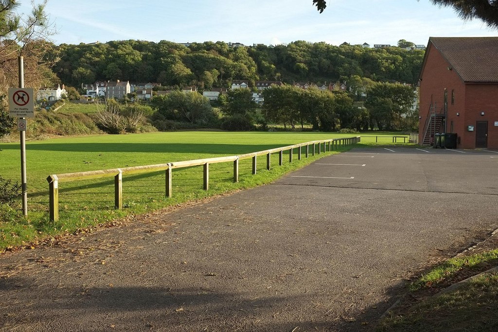 Knee rail fencing by a field of grass.