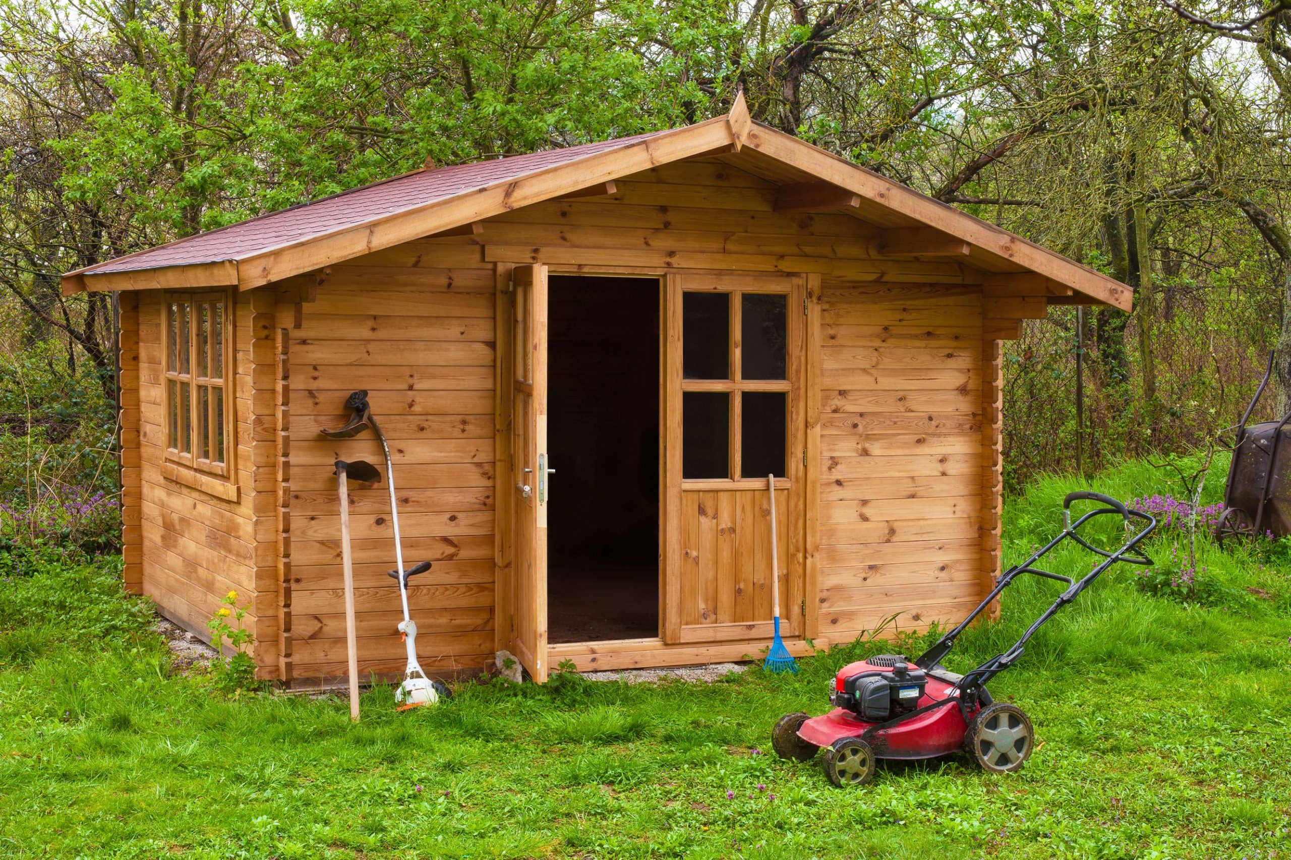 Lawn mower outside a large shed.