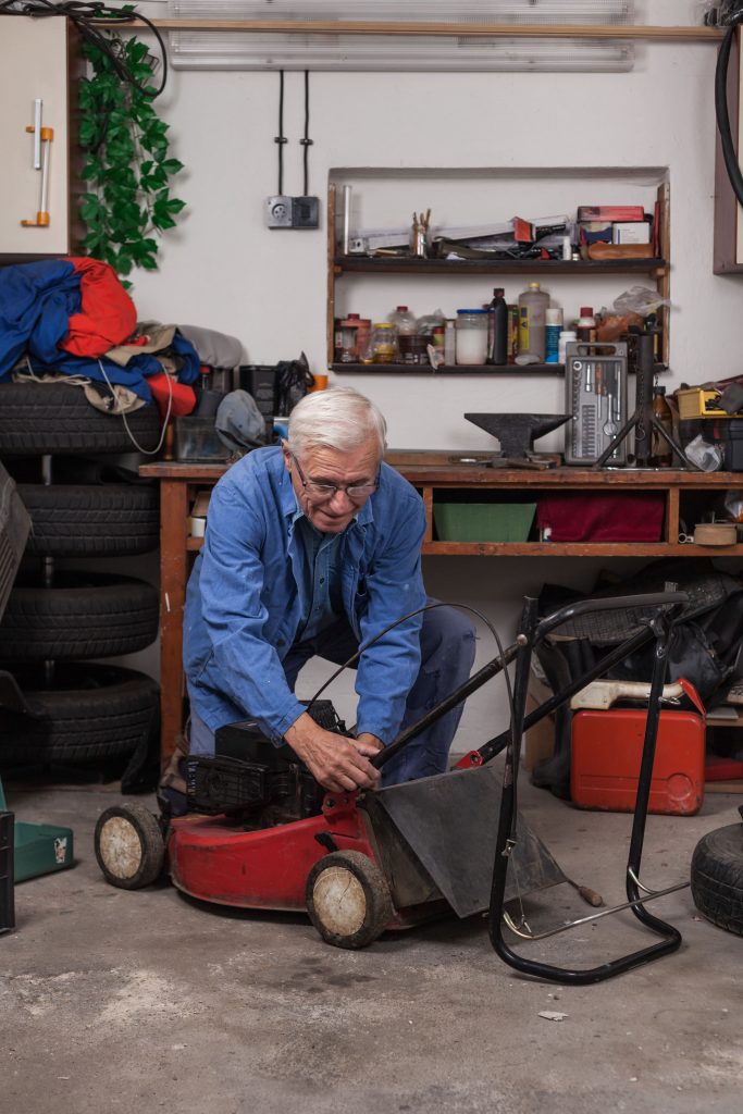 Lawn mower outside a garage being prepared for storage.