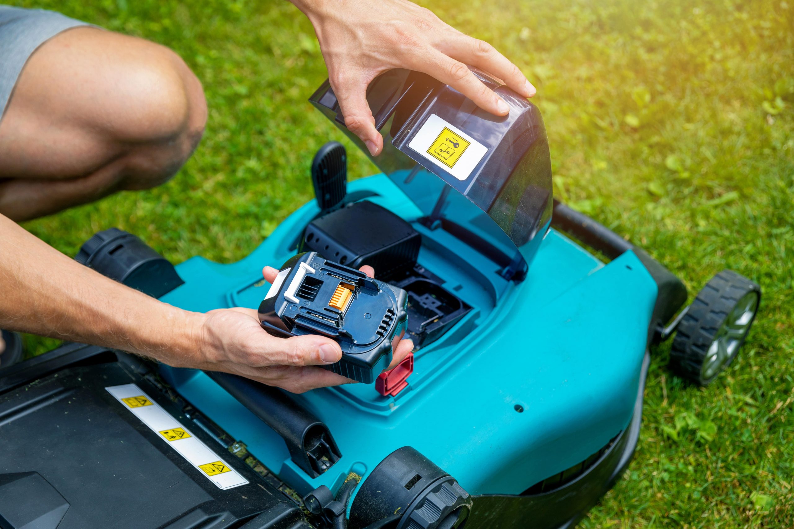 Man changing the battery on a cordless lawn mower.