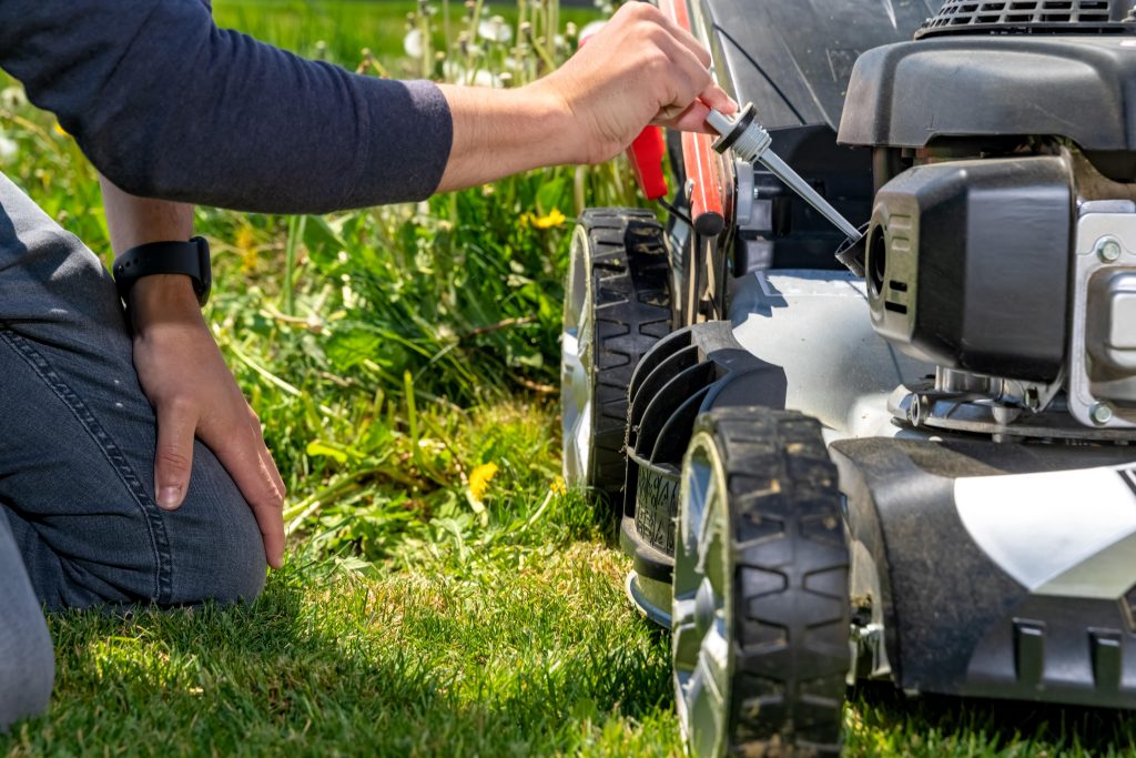 Man checking the oil level in his lawn mower.