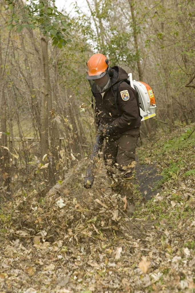 Man clearing a path with a petrol leaf blower.