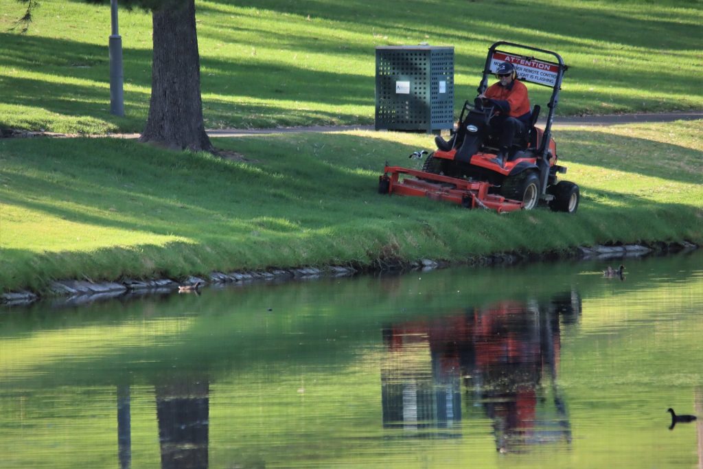 Man cutting lawn with a ride-on mower.