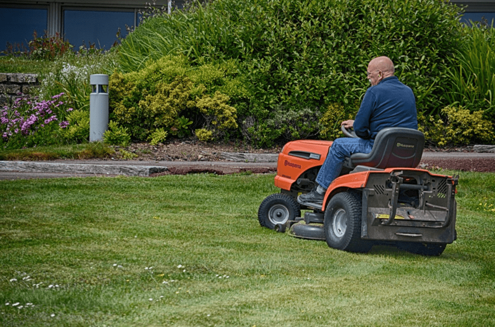 Man mowing the lawn with a lawn tractor.