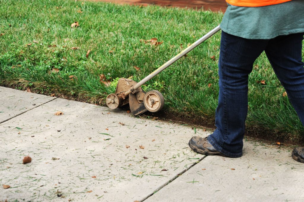 Man trimming the edge of a lawn.