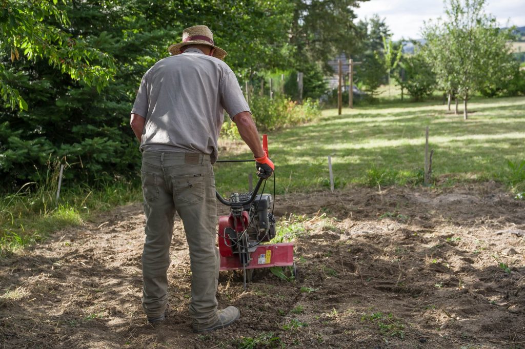 Man using a tiller on an allotment.