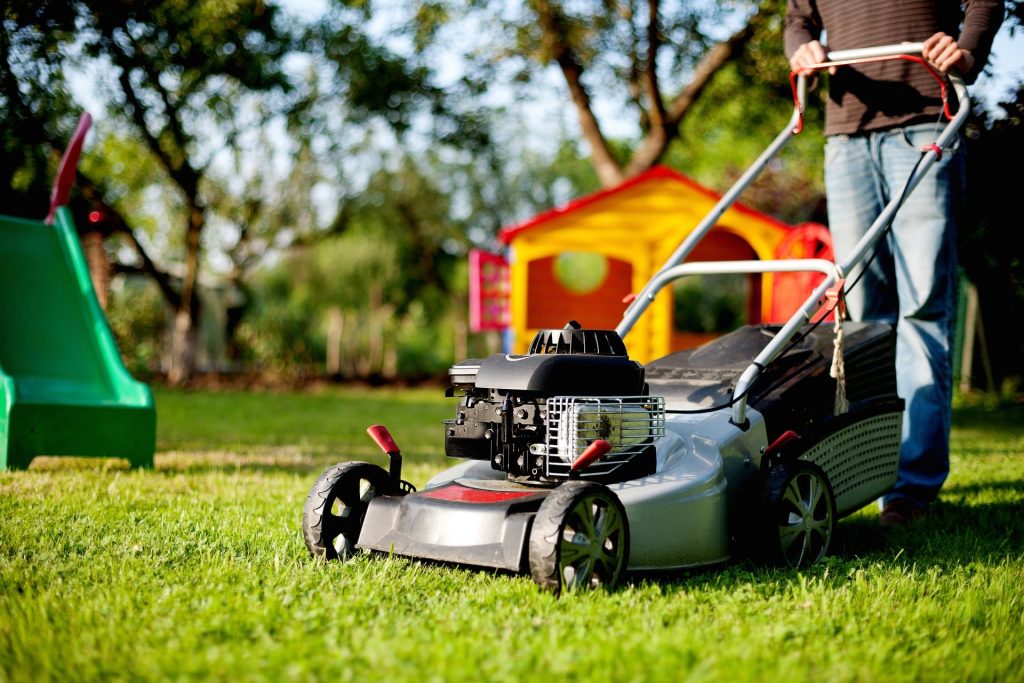 Man using a roller lawn mower.