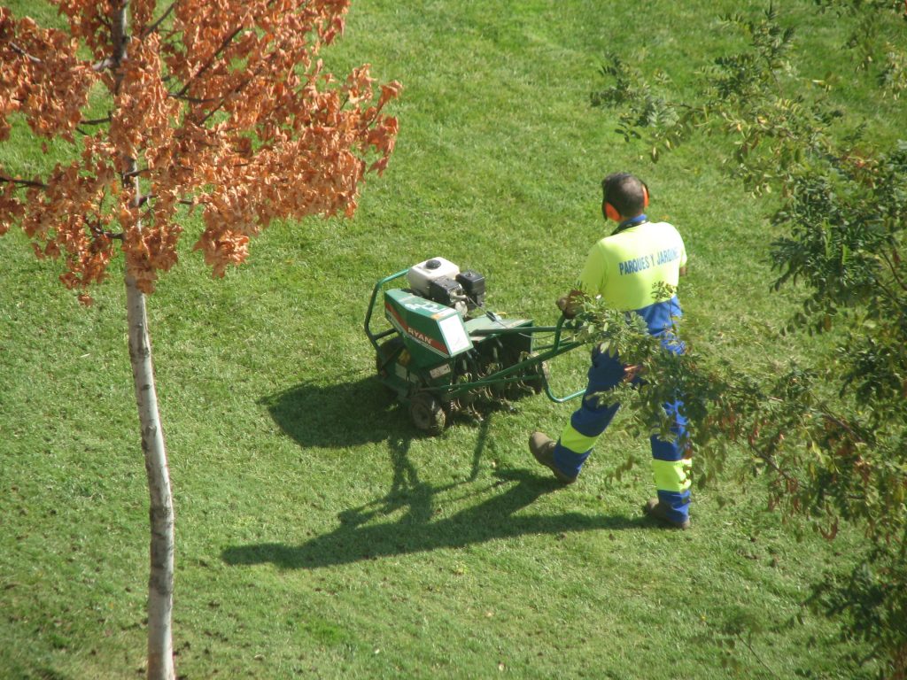 Man using a walk behind powered aerator.