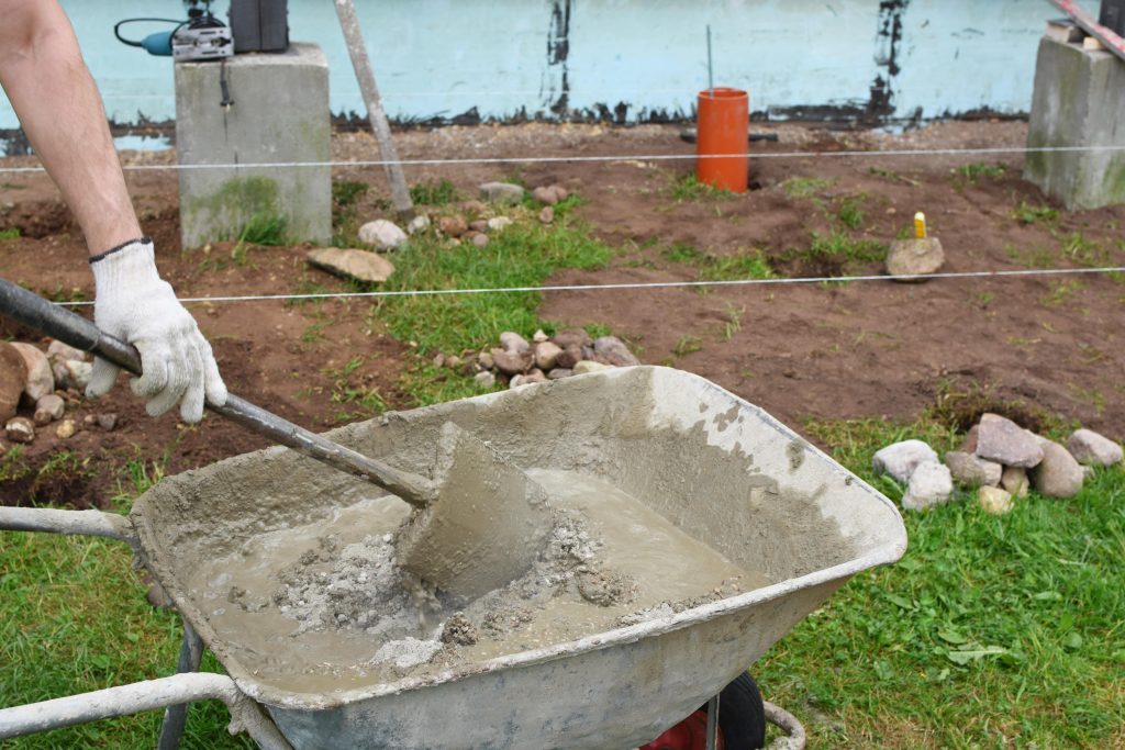 Mixing concrete in a wheelbarrow.