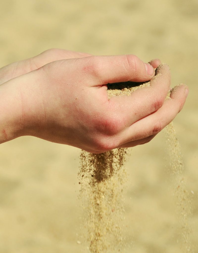 Person holding sand in their hands.