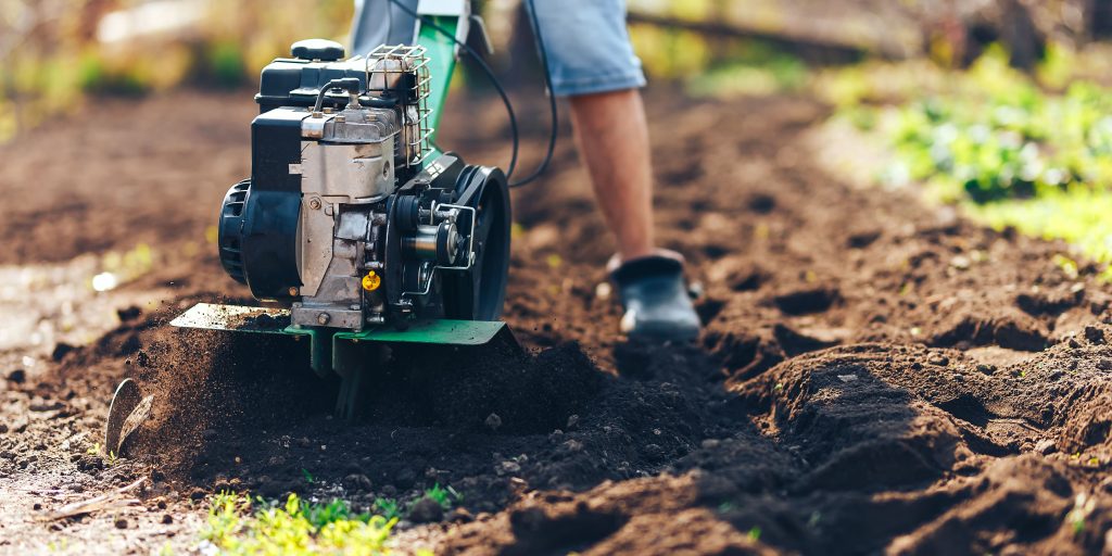 Man using a petrol rotavator.