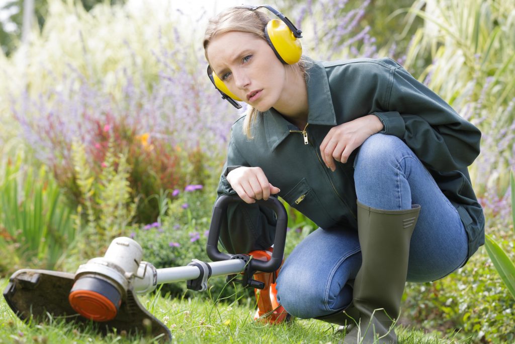Woman using a cordless strimmer.