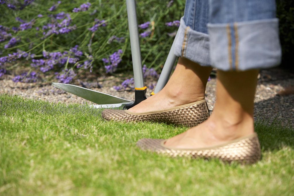 Woman trimming grass edge with shears.