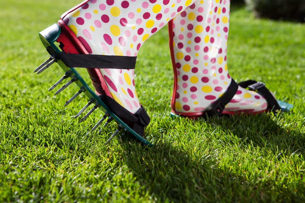 Woman walking in lawn aerator shoes.